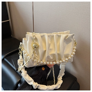 Detail of glossy pleated leather cream handbag with pearl chain and gold hardware