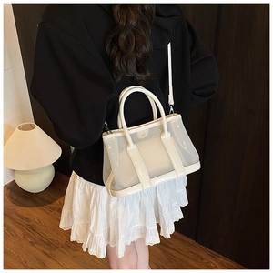 Détail du sac seau blanc semi-transparent avec poignées en cuir et bandoulière longue