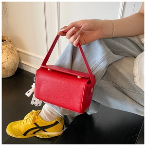 Detailed close-up of a red litchi grain leather handbag with gold metal hardware