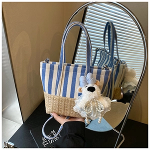 Detail of nautical striped canvas tote with straw bottom and cute bear charm pendant
