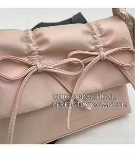 Vue détaillée du sac en cuir rose avec nœuds élégants et foulard imprimé sur l'anse