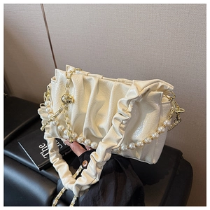 Detail of cream pleated cloud bag with elegant pearl chain and soft leather texture