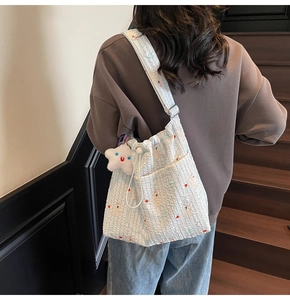 Détail du sac bandoulière en nylon rayé avec broderie animale et pendentif étoile en peluche