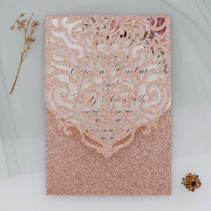 Détail d'une invitation de mariage découpée au laser en or rose avec insert floral et dentelle