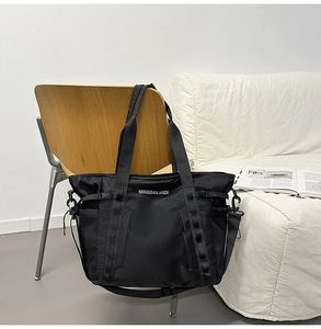 Detail of black tactical gym bag with side mesh pocket and nylon webbing on a wooden chair