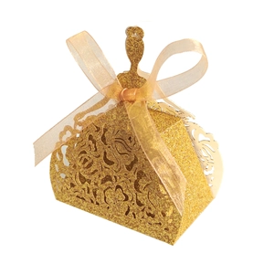 Détail des motifs de fleurs découpés au laser sur une boîte cadeau dorée en forme de robe