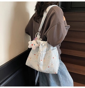 Détail du sac à bandoulière plissé bleu clair en nylon avec un charm étoile sur un escalier