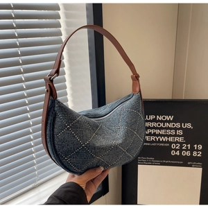 Detail of blue denim shoulder bag with rhinestone lattice pattern and brown leather strap