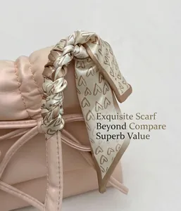 Détail d'un sac à main en cuir rose avec un foulard en soie à motifs de cœurs sur l'anse