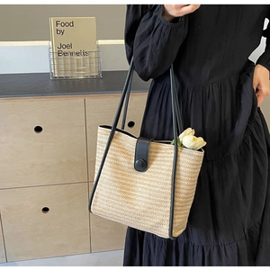 Detail of woven straw tote bag with black leather strap and round buckle closure