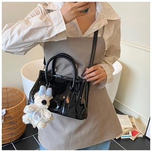 Détail du sac seau noir brillant avec breloque chien en peluche lors d'un selfie miroir