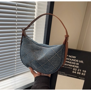 Detail showing vintage denim saddle bag with silver metal rivets and brown leather trim