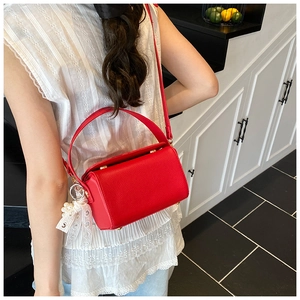 Detail of red pebbled leather handbag with pearl lace pendant and metal lock clasp