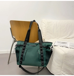 Detail of a dark green waterproof travel tote bag hanging on a chair in a home setting