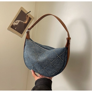Close-up of denim hobo bag with silver studs, diamond patterns and leather shoulder strap