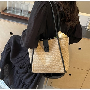 Detail of woven tote bag with black leather strap and tulip decoration in a lifestyle setting