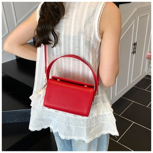 Detail of red lychee leather handbag with elegant white lace and pearl pendant decor