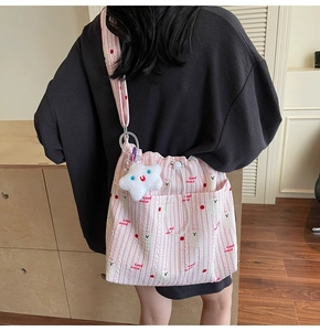 Détail du sac à bandoulière en nylon rayé rose avec cordon et pendentif nuage