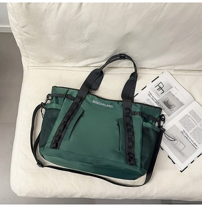 Macro detail of dark green waterproof nylon travel bag with brand logo on a white sofa