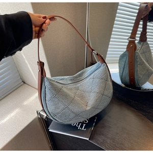 Detail of light blue denim hobo bag with rhinestone patterns and brown leather strap