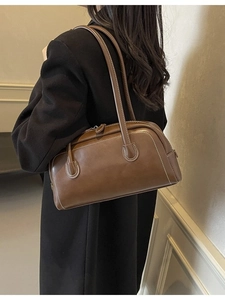 Classic dark brown leather Boston bag with white stitching shown on shoulder