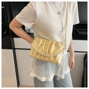Detail of light yellow ruched cloud bag with pearl chain shown as a crossbody