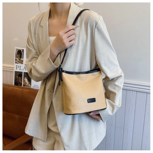 Detail of hand-woven beige straw bag with dark brown leather trim and shoulder strap
