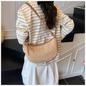 Close-up of woven straw shoulder bag with leather trim and knotted strap detail