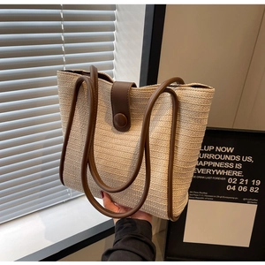 Close-up of contrast woven tote bag showing fine beige texture and brown leather strap