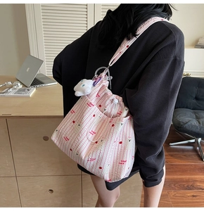 Détail du sac en nylon rayé rose avec imprimé cerise et breloque lapin en peluche