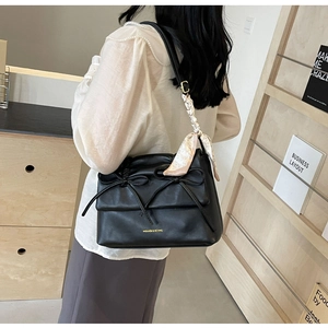 Détail du sac noir à nœuds avec un foulard en soie élégant enroulé sur l'anse