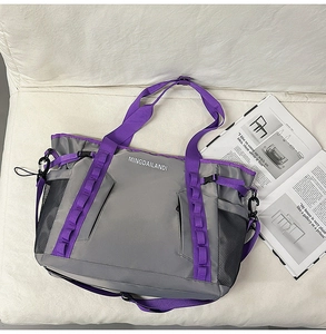 Detail of dark grey travel bag showing purple webbing straps and mesh side pockets