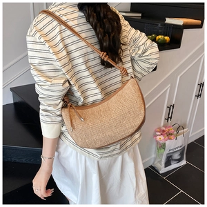 Detailed shot of a woven hobo bag with knotted leather strap and straw texture finish