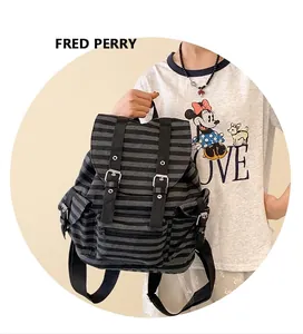 Detail of vintage striped canvas backpack featuring leather buckle closures and side pockets