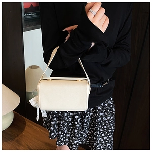 Detail of off-white crossbody bag with litchi grain texture and gold cylinder clasps