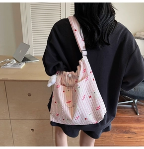 Vue arrière du sac bandoulière en nylon à rayures roses avec imprimés et pendentif