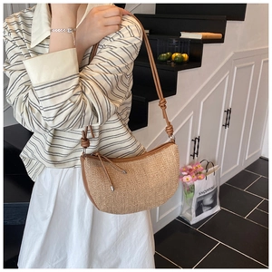 Detail of woven crescent shoulder bag with leather knotted strap and texture