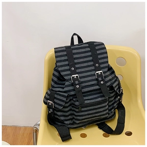 Macro detail of striped canvas backpack showing flap pockets with metal buckles