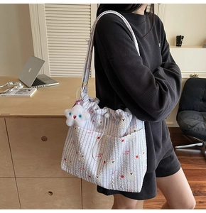 Détail d'un grand cabas en nylon rayé avec motif alpaga et pendentif étoile en peluche