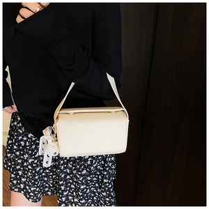 Detail of cream white leather mini handbag with lace bow and pearl charm accent