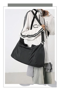 Mannequin portant un grand sac de voyage noir avec bandoulière réglable et poche zippée latérale