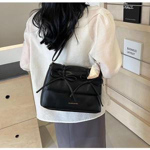 Détail du sac noir à nœuds avec foulard rose décoratif porté par le mannequin