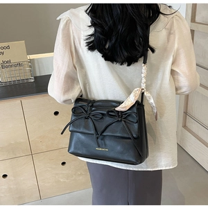Détail du sac à nœud noir avec foulard en soie à cœurs et lettrage doré sur le devant