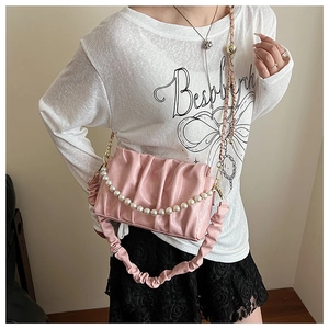 Detailed macro view of pink pleated cloud bag with pearl chain and golden metal clasp