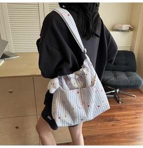 Détail du sac cabas en nylon rayé avec imprimé cœur, cordon de serrage et pendentif peluche