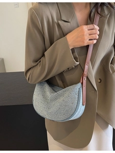 Light blue denim crescent shoulder bag with silver rhinestones on khaki suit
