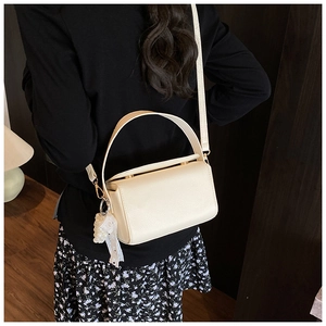 Detail of cream leather box handbag with lace pearl charm and gold hardware