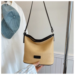Detail showing beige woven raffia shoulder bag with black leather trim and logo