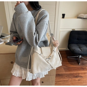 Detail of cream hobo shoulder bag with magnetic flap and cute brown plush bear charm