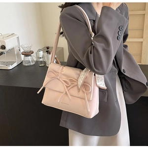 Détails des nœuds roses et du foulard à cœurs sur un sac à bandoulière plissé